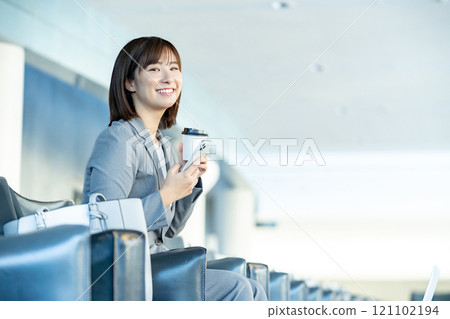 Office lady looking at smartphone, woman waiting for someone in airport lobby, office lady, working Office lady looking at smartphone, woman waiting for someone in airport lobby, office lady, working 121102194