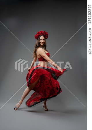Dancer in vibrant red dress twirling gracefully with floral headpiece 121102265