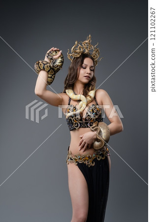 Woman elegantly poses with exotic snakes in a striking artistic display 121102267