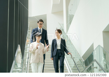 一個穿著西裝的男人和一個女人走下辦公室的樓梯 一個穿著西裝的男人和一個女人走下辦公室的樓梯 121102300