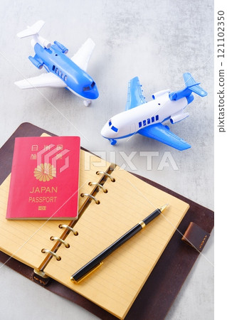 An image of a 10-year red passport, an airplane, and a personal organizer planning a long vacation overseas trip 121102350