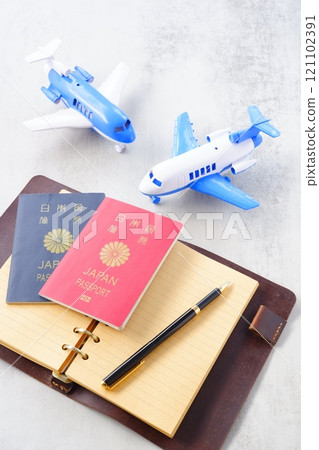 一張帶著護照(紅色 10 年,海軍藍色 5 年)、一架飛機和一本打開的筆記本計畫出國旅行的圖片。 一張帶著護照(紅色 10 年,海軍藍色 5 年)、一架飛機和一本打開的筆記本計畫出國旅行的圖片。 121102391