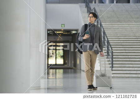 一名 40 多歲的男子拎著手提包走路時攜帶智慧型手機 一名 40 多歲的男子拎著手提包走路時攜帶智慧型手機 121102728