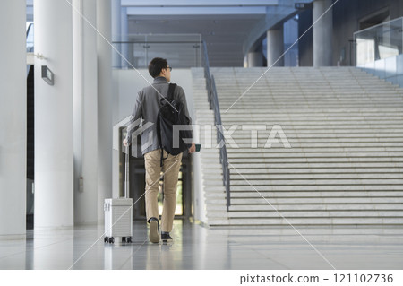 A man in his 40s walking with a carry bag, back view A man in his 40s walking with a carry bag, back view 121102736