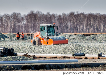 Road roller dredges rubble on road construction Road roller dredges rubble on road construction 121102826