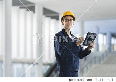 穿著工作服的中年男子拿著平板電腦，看著相機，肖像 121102881