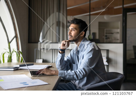 Businessman reflecting on work-related issue seated at desk with laptop Businessman reflecting on work-related issue seated at desk with laptop 121103767