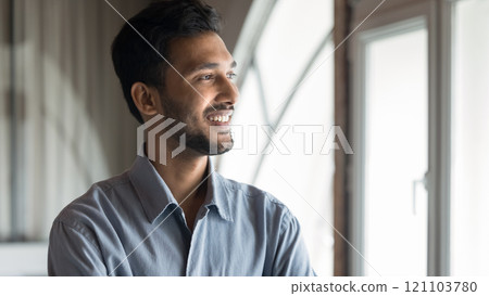 Indian man looking out of window with thoughtful expression 121103780