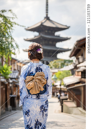 A woman in a yukata standing with a five-story pagoda in the background 121103789