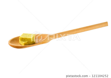 Bouillon cube in a wooden spoon isolated on a white background. 121104252