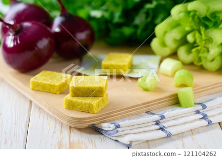chicken bouillon cubes and fresh vegetables for soup on white wooden table, selective focus. 121104262