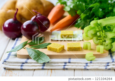 chicken bouillon cubes and fresh vegetables for soup on white wooden table, selective focus. 121104264