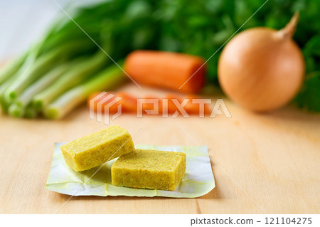 chicken bouillon cubes and fresh vegetables for soup on white wooden table, selective focus. chicken bouillon cubes and fresh vegetables for soup on white wooden table, selective focus. 121104275