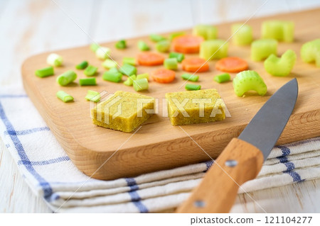 chicken bouillon cubes and fresh vegetables for soup on a cutting board , selective focus. chicken bouillon cubes and fresh vegetables for soup on a cutting board , selective focus. 121104277