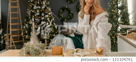 Woman Kitchen Christmas decor in white shirt, peeling tangerines. Illustrating New Year's mood holiday preparations 121104761
