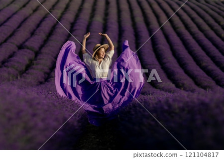 A woman in a purple dress is dancing in a field of lavender A woman in a purple dress is dancing in a field of lavender 121104817