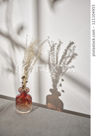 Warm sunlight streaming in through the window, beige background, flowers, vases, and a table with plants. Harmony of light and shadow. 121104955