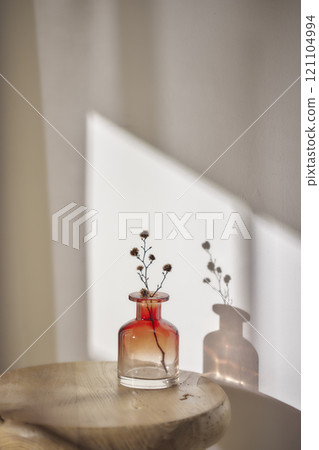 Warm sunlight streaming in through the window, beige background, flowers, vases, and a table with plants. Harmony of light and shadow. Warm sunlight streaming in through the window, beige background, flowers, vases, and a table with plants. Harmony of light and shadow. 121104994