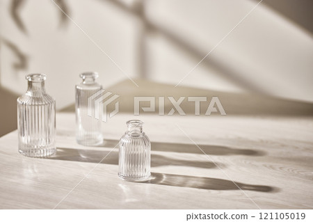 Warm sunlight streaming in through the window, beige background, flowers, vases, and a table with plants. Harmony of light and shadow. 121105019