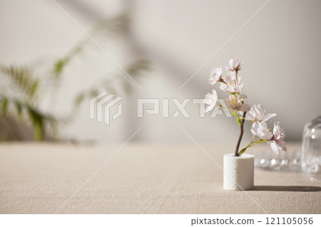 Warm sunlight streaming in through the window, beige background, flowers, vases, and a table with plants. Harmony of light and shadow. 121105056