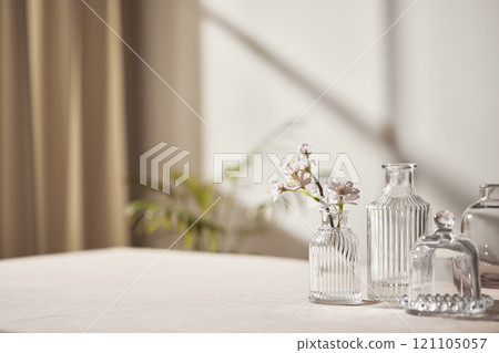 Warm sunlight streaming in through the window, beige background, flowers, vases, and a table with plants. Harmony of light and shadow. 121105057