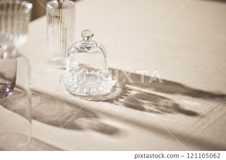Warm sunlight streaming in through the window, beige background, flowers, vases, and a table with plants. Harmony of light and shadow. 121105062