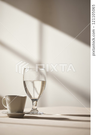 Warm sunlight streaming in through the window, beige background, flowers, vases, and a table with plants. Harmony of light and shadow. 121105065