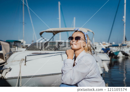 Woman in white shirt in marina , surrounded by several other boats. The marina is filled with boats of various sizes, creating a lively and picturesque atmosphere. 121105574