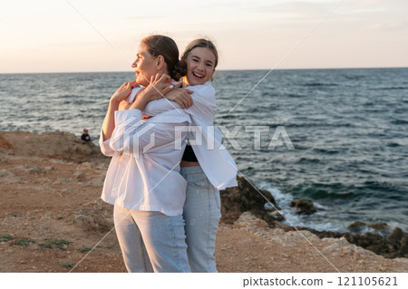 Mother Daughter Beach Sunset - Happy mother and daughter embracing at sunset on a beach. Mother Daughter Beach Sunset - Happy mother and daughter embracing at sunset on a beach. 121105621