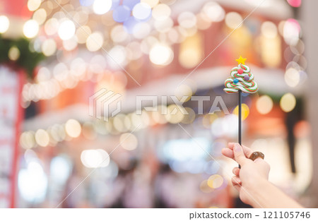 Woman hand holding Christmas candy with celebration bokeh background 121105746