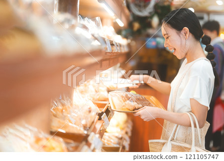 Happy smiling customer asian woman choosing whole grain bread at bakery shop 121105747