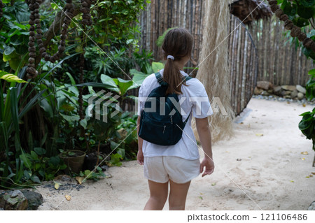 A young teenage girl is walking forward. The view from the back .A tropical path. A young teenage girl is walking forward. The view from the back .A tropical path. 121106486