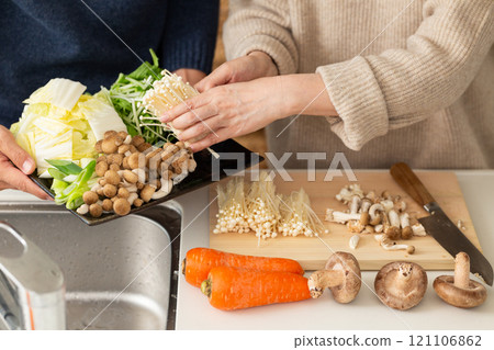 A middle-aged to senior couple preparing hotpot in the kitchen 121106862