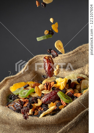 Dried tropical fruits and nuts in burlap bag. 121107604