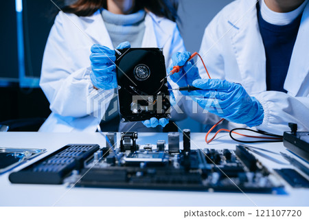 Hard disk drive on the technicians desk and a computer motherboard as a component. 121107720