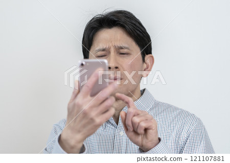 Man having difficulty seeing smartphone screen, presbyopia, eye strain, tired eyes Man having difficulty seeing smartphone screen, presbyopia, eye strain, tired eyes 121107881