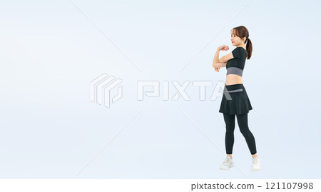 Full-body photo of a woman in sportswear stretching 121107998