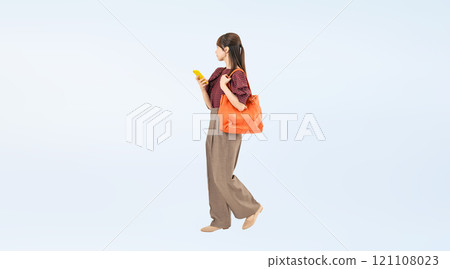 Full-body photo of a woman in casual wear walking with a smartphone 121108023