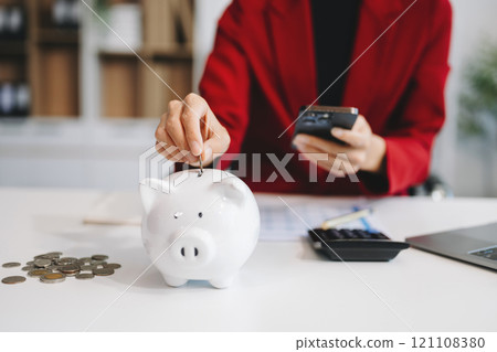 Women are putting coins in a piggy bank for a business that grows for profit and saving money for the future. Women are putting coins in a piggy bank for a business that grows for profit and saving money for the future. 121108380