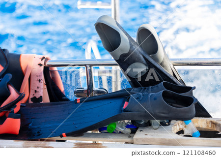 Many multi-colored rubber fins for swimming, diving, sports lie in a basket, a box on a floating boat, a ship, a cruise liner in a tropical warm southern resort. 121108460