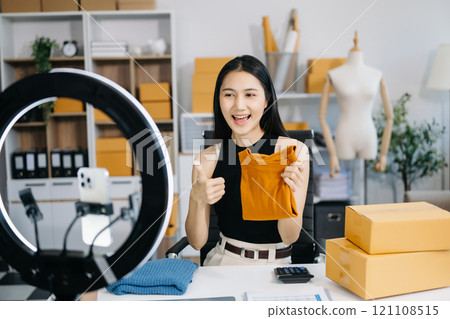 Fashion blogger concept, Young Asian women selling clothes on video streaming.Startup small business SME, using smartphone or tablet taking receive and checking Fashion blogger concept, Young Asian women selling clothes on video streaming.Startup small business SME, using smartphone or tablet taking receive and checking 121108515
