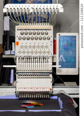 Intricate embroidery machine in action creating colorful designs in a workshop setting 121108620