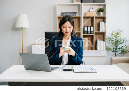 Young beautiful woman typing on tablet and laptop while sitting at the working Young beautiful woman typing on tablet and laptop while sitting at the working 121108889