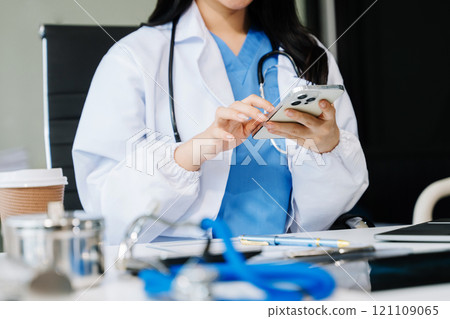 Dentist sitting at table with jaw samples tooth model and working with tablet and laptop in dental modern office Dentist sitting at table with jaw samples tooth model and working with tablet and laptop in dental modern office 121109065