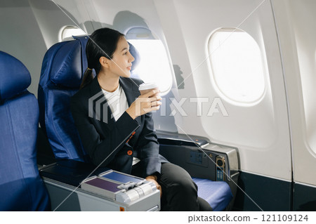 Asian businesswoman or entrepreneur in a formal suit on an airplane sitting in business class using a phone, computer laptop. Travel in style, work 121109124