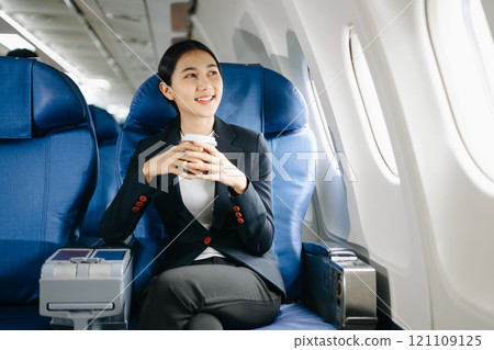 Asian businesswoman or entrepreneur in a formal suit on an airplane sitting in business class using a phone, computer laptop. Travel in style, work 121109125