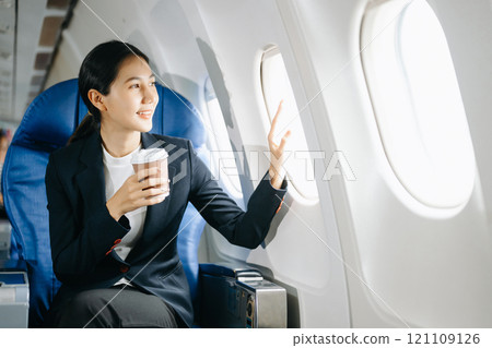 Attractive Asian female passenger of airplane sitting in comfortable seat while working laptop and tablet with mock up area using wireless connection. Attractive Asian female passenger of airplane sitting in comfortable seat while working laptop and tablet with mock up area using wireless connection. 121109126