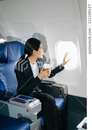Attractive Asian female passenger of airplane sitting in comfortable seat while working laptop and tablet with mock up area using wireless connection. 121109127