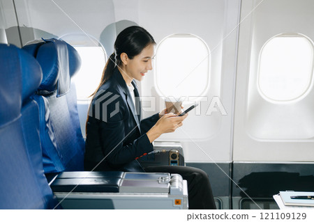Attractive Asian female passenger of airplane sitting in comfortable seat while working laptop and tablet with mock up area using wireless connection. 121109129