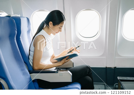 ttractive Asian female passenger of airplane sitting in comfortable seat while working laptop and tablet in style, work with grace. ttractive Asian female passenger of airplane sitting in comfortable seat while working laptop and tablet in style, work with grace. 121109152